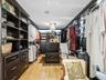 Custom walk-in closet featuring floor-to-ceiling dark wood cabinetry, integrated storage island with drawers, built-in desk workstation, wood-finish f