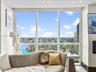 Floor-to-ceiling windows featuring expansive urban and waterway scenery, complemented by recessed ceiling lighting