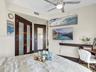Custom dark-wood doors featuring frosted glass panels, brushed metal ceiling fan with integrated lighting, and horizontal wood accent shelf
