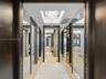 High-gloss dark wood doorways with metal inlay, full-length mirror paneling, recessed lighting, and a crystal chandelier
