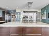 Kitchen featuring a large central island with a quartz countertop, flat-panel wood-finish cabinetry, built-in stainless steel appliances, and a ceilin