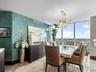 Dining area featuring floor-to-ceiling windows, polished stone flooring, custom textured wall finish, and a suspended crystal chandelier