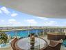 Covered balcony featuring natural stone flooring and a glass-paneled metal railing