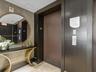 Elevator lobby featuring custom dark wood door surround, textured concrete-style wall finish, and stone flooring