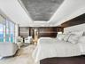Floor-to-ceiling windows, custom dark wood-finish wall paneling, recessed tray ceiling with integrated lighting, and polished stone flooring