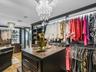 Custom walk-in closet featuring built-in dark wood cabinetry, integrated LED shelf lighting, a center island with a dark countertop, and decorative cr