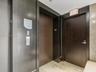 Elevator landing featuring dark wood-finish door frames, a metallic elevator door, and light-toned stone tile flooring