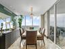 Floor-to-ceiling windows, polished stone flooring, recessed ceiling lighting, and a tiered crystal pendant fixture