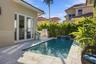 Backyard featuring an in-ground swimming pool with a tiled water feature, stone-paver decking, and a built-in outdoor grill station