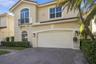 Stucco exterior featuring a paver driveway, arched windows, decorative metal balcony, and tile roofing