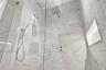 Walk-in shower featuring large-format light veined tile, frameless glass enclosure, ceiling-mounted rainfall showerhead, adjustable handheld shower wa