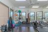 Dedicated fitness area featuring dark wood-finish flooring, rubberized gym flooring, floor-to-ceiling wall mirror, recessed ceiling lighting, and mult