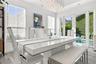Dining area featuring large-format tile flooring, multi-globe chandelier, crisp white walls, horizontal window blinds, and glass doors opening to an o