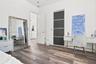 Room featuring wood-finish flooring, recessed ceiling lighting, and a closet with sliding dark-toned panels and metallic trim