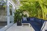 Outdoor patio featuring natural stone pavers, double-glass swing doors, and perimeter privacy wall with lush tropical greenery