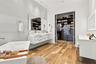 Floating white dual-sink vanity with rectangular vessel sinks, freestanding deep-soaking tub, wood-finish flooring, and built-in closet system with sl