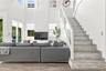 Double-height ceiling, open floor plan featuring wood-finish flooring, staircase with tiled risers, white railing, and glass paneled walls, and multip