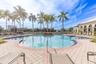 In-ground swimming pool featuring a curved perimeter, stepped entry, central garden island, and surrounding paver patio with a colonnade structure