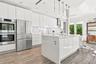 Modern kitchen featuring high-gloss white cabinetry, a center island with a stone-finish waterfall countertop, stainless steel double wall ovens, wood