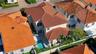 Aerial perspective of a multi-story residence featuring a terracotta-style tile roof, a private swimming pool, and a walled rear perimeter
