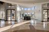 Rotunda interior featuring polished stone flooring, a multi-paneled curved window wall, and dual glass-paned double doors