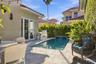Outdoor living space featuring a tiled patio, private swimming pool with a stone-accented water feature, built-in stainless steel grill, and manicured