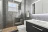 Bathroom featuring large-format dark grey wall tile, a glass-enclosed shower with a rainfall showerhead, a floating vanity with a textured cabinet fin