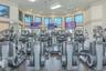Fitness center featuring a curved wall of windows, multiple elliptical machines, treadmills, and ceiling-mounted televisions