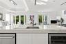 Kitchen island featuring a stone-look countertop, undermount sink with a high-arch faucet, built-in stainless steel dishwasher, integrated wine refrig