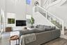 Double-height ceiling, glass-paneled staircase railing, wood-finish flooring, and expansive windows
