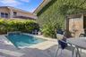 Outdoor space featuring a swimming pool with a built-in water feature, stone paver decking, decorative wood-carved gate, and exterior wall with climbi