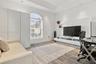 Tray ceiling with recessed lighting, arched window with horizontal blinds, built-in floor-to-ceiling cabinetry, and wood-finish flooring