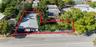 Expansive parcel featuring a structured building, generous green space, mature trees, palm trees, and perimeter fencing