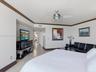 Neutral wall paint, crown molding, stone flooring, and a modern metal ceiling fan with integrated lighting