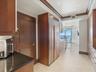 Kitchen featuring custom wood cabinetry, integrated stainless steel refrigerator, dark stone countertops, crown molding, and stone tile flooring