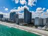 High-rise coastal architecture featuring glass curtain walls and direct access to an expansive sandy beach