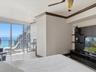 Floor-to-ceiling glass panel windows, built-in media console with tiered shelving, ceiling fan, crown molding, and polished stone flooring