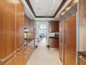 Galley kitchen featuring custom flat-panel wood cabinetry, integrated stainless steel refrigerator, black stone countertops, tile flooring, and recess
