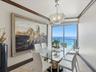 Dining space featuring stone tile flooring, crown molding, a custom pendant light fixture, and a floor-to-ceiling glass door opening to an oceanfront 