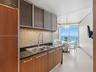 Kitchen featuring wood-finish cabinetry, a mosaic tile backsplash, dark solid-surface countertops, an integrated stainless steel refrigerator, and lar