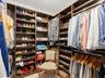 Walk-in closet featuring extensive dark wood-finish cabinetry, floor-to-ceiling adjustable shelving, integrated garment hanging rods, and tile floorin