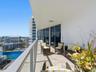 Covered balcony featuring stone-finish flooring, a glass-panel railing, and floor-to-ceiling sliding glass doors