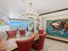 Intricate crystal chandelier, stone flooring, crown molding, and large-format glass panels with ocean scenery