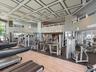 Fitness center featuring a coffered ceiling, wood-finish flooring, recessed lighting, and a mezzanine level with metal railings