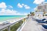 Expansive stone-paved terrace featuring a glass panel railing and direct oceanfront access