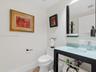 Floating vanity featuring a frosted glass countertop with an integrated sink and matte black metal frame, paired with a matching rectangular wall mirr