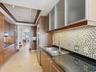 Kitchen featuring wood cabinetry, frosted-glass upper cabinet doors, dark solid-surface countertops, mosaic tile backsplash, and stainless steel doubl