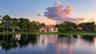 Waterfront residence featuring a tile roof, expansive lawn, mature landscaping, and palm trees