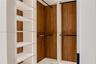 Custom walk-in closet featuring white open shelving, wood-finish paneling, and matte black hanging rods