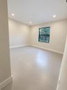Interior space featuring large-format tile flooring, neutral wall tones, recessed lighting, and a window with a black frame